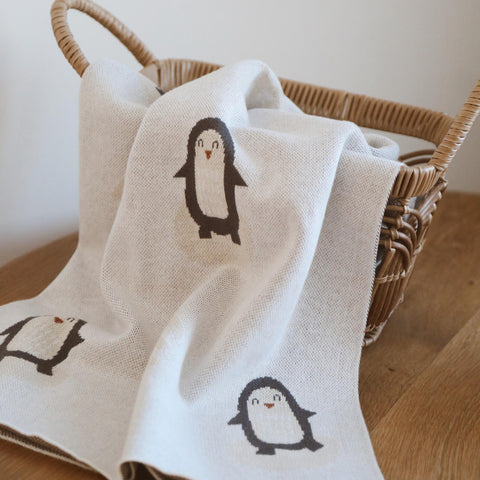 Arctic Penguins blanket displayed in woven basket showing soft knit texture