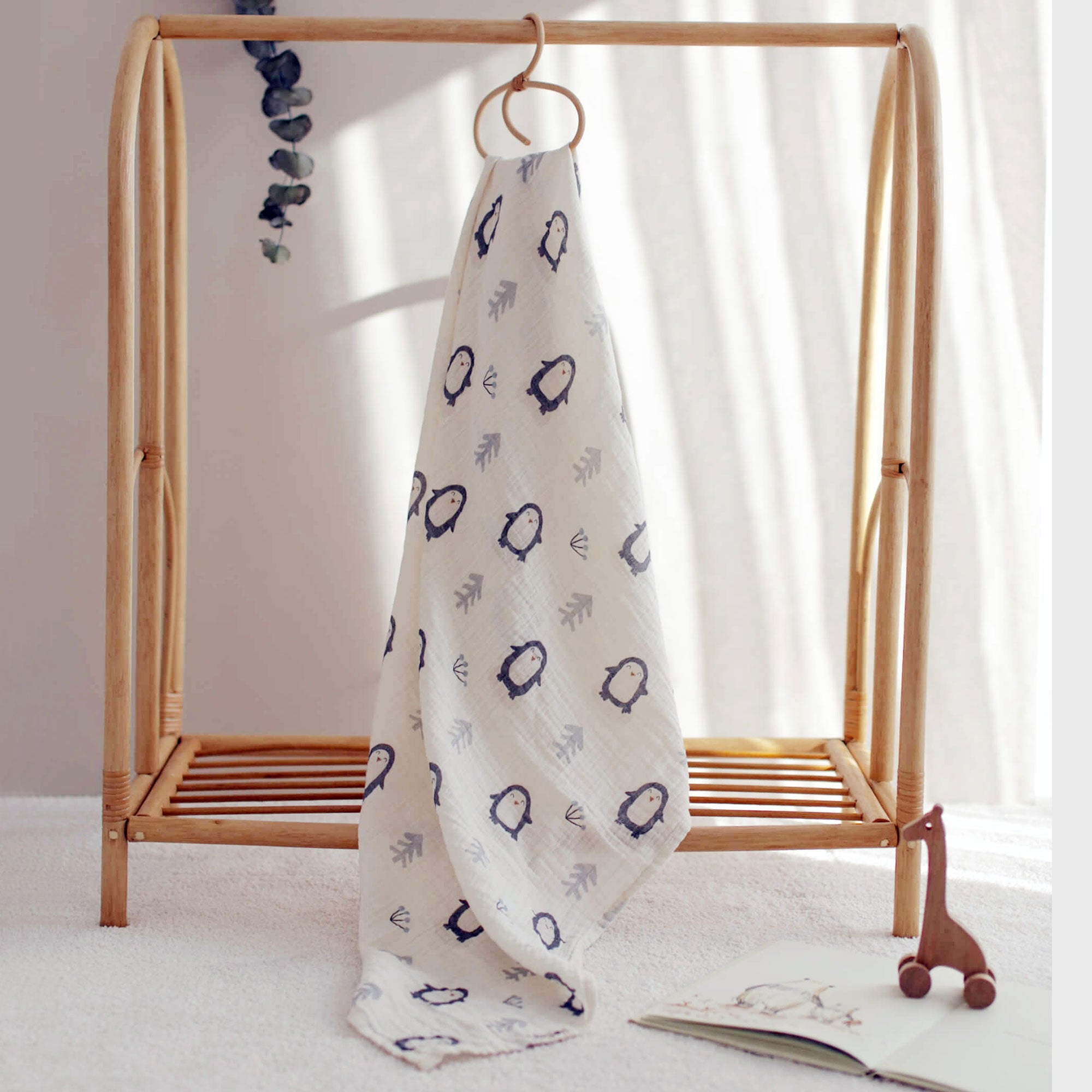 Penguin print swaddle hanging on bamboo baby clothes rack