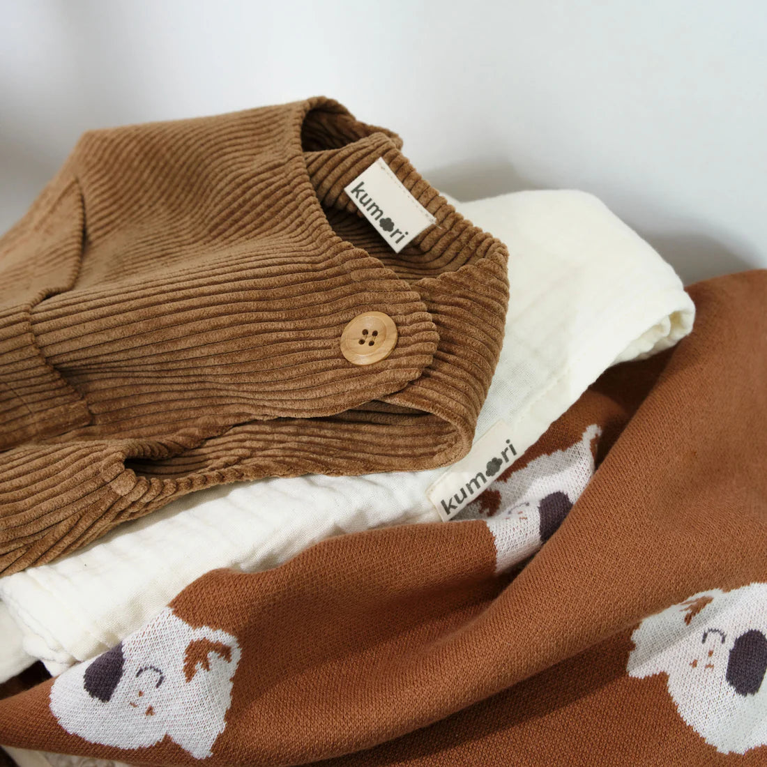 Folded brown corduroy baby overalls styled with other baby clothes