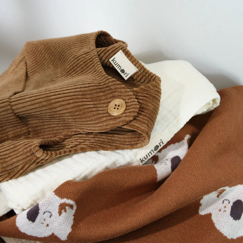 Folded brown corduroy baby overalls styled with other baby clothes