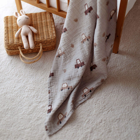 Cars swaddle and toy basket on a soft white rug