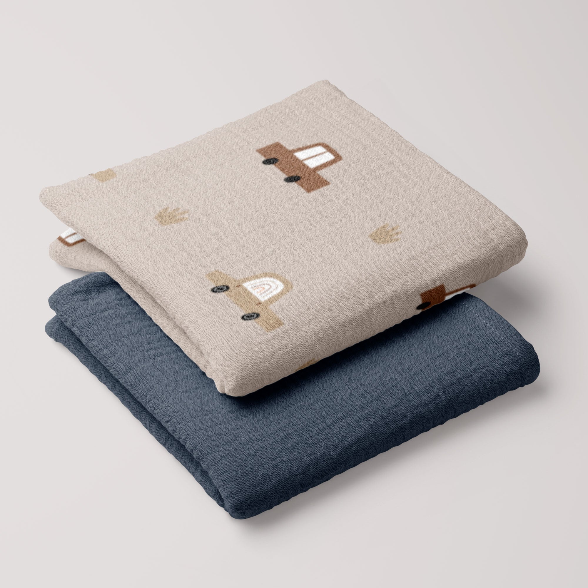 Cars muslin swaddle and navy blue muslin blanket stacked together