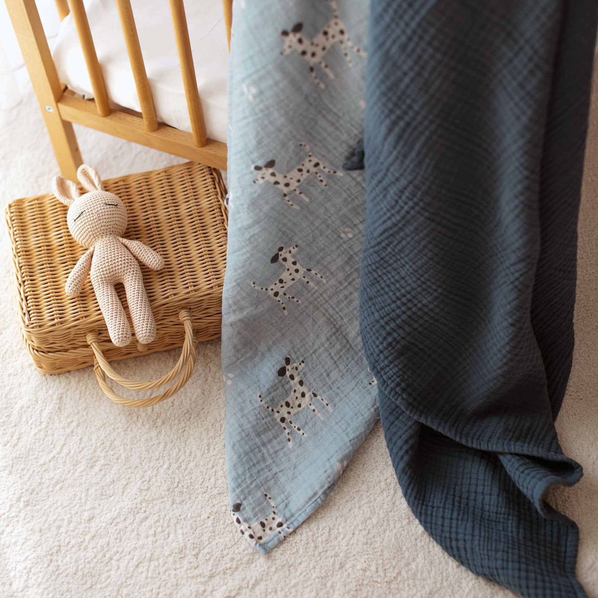 Dalmatian swaddle and navy muslin blanket draped over crib rail