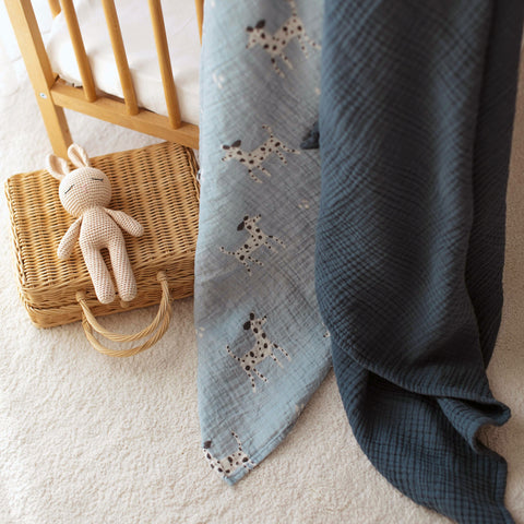 Dalmatian swaddle and navy muslin blanket draped over crib rail