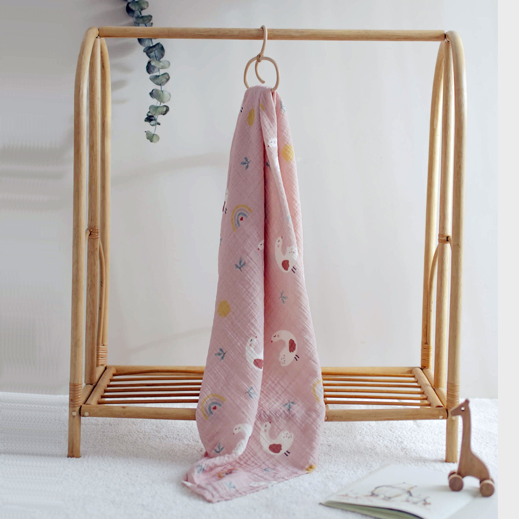 Pink goose print muslin swaddle hanging from a rack
