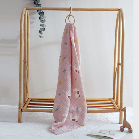 Pink goose print muslin swaddle hanging from a rack