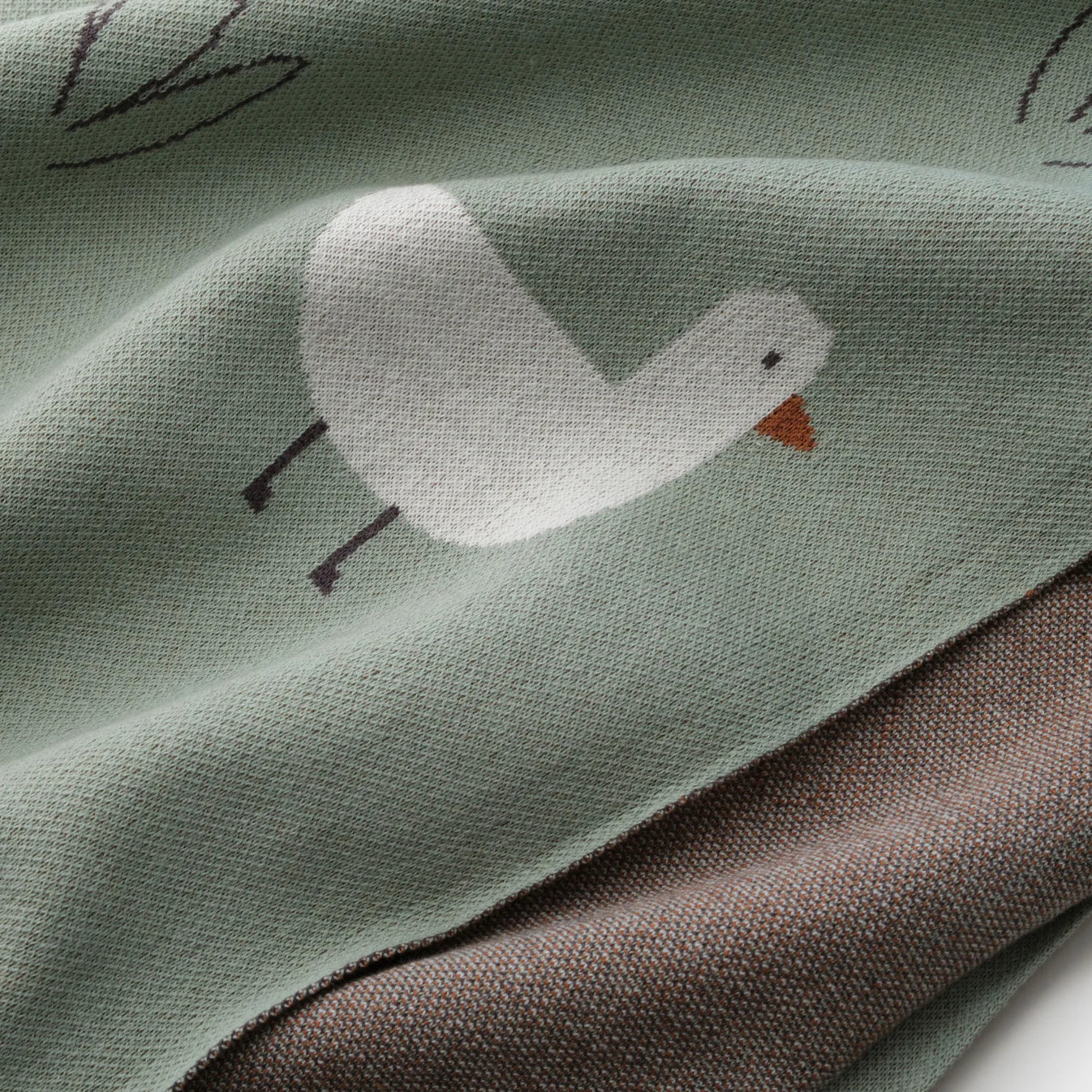 Close-up of duck pattern on soft green organic cotton knit baby blanket