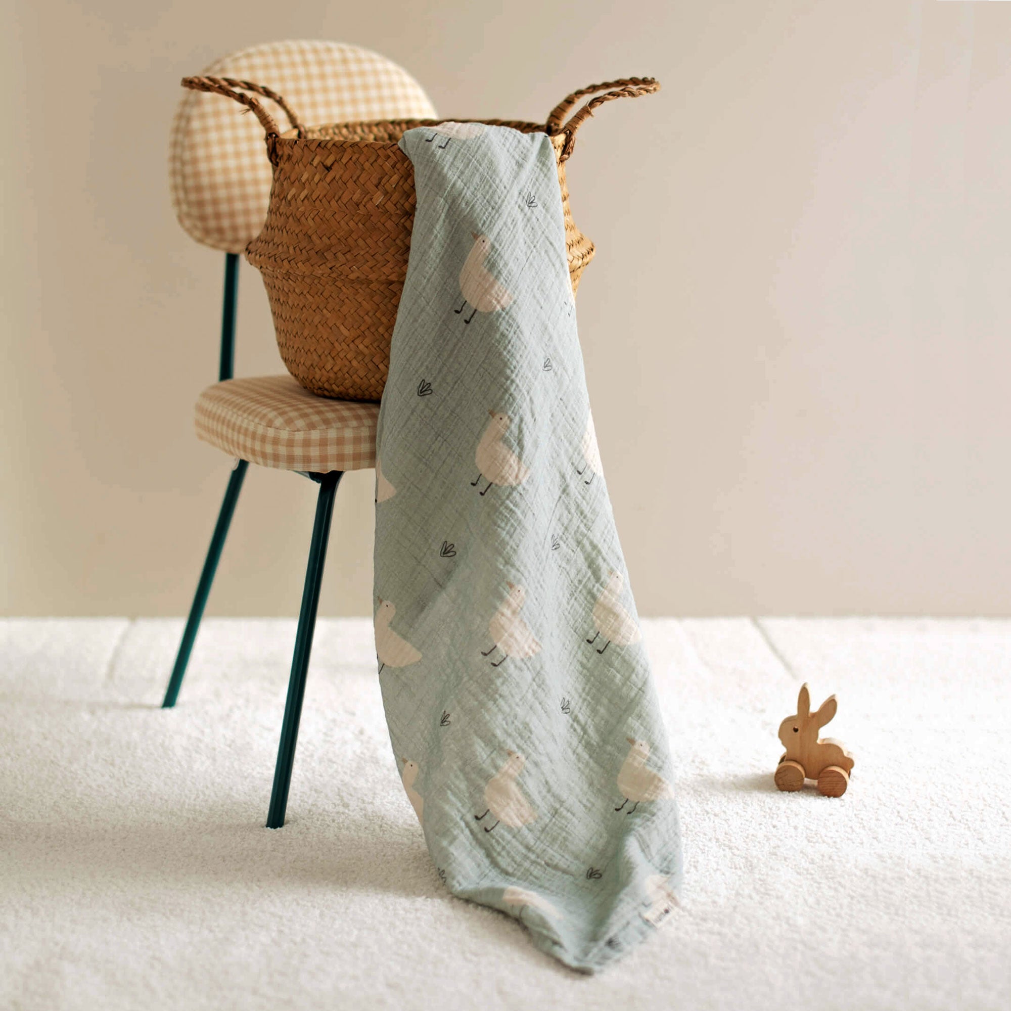Minty duck swaddle upright with toy basket in background