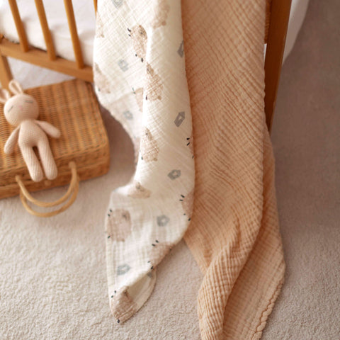 Cream 4-ply muslin baby blanket styled draped over wooden crib