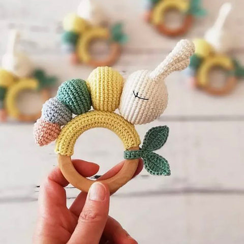 Person holding colorful crochet caterpillar teething rattle