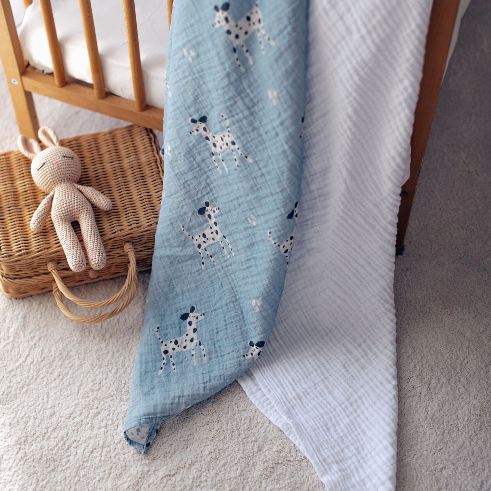 Dalmatian print baby swaddle styled next to crib in soft nursery light