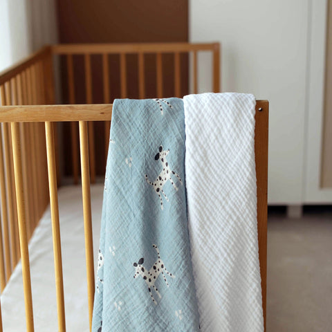 Dalmatian print swaddle and white blanket over crib rail