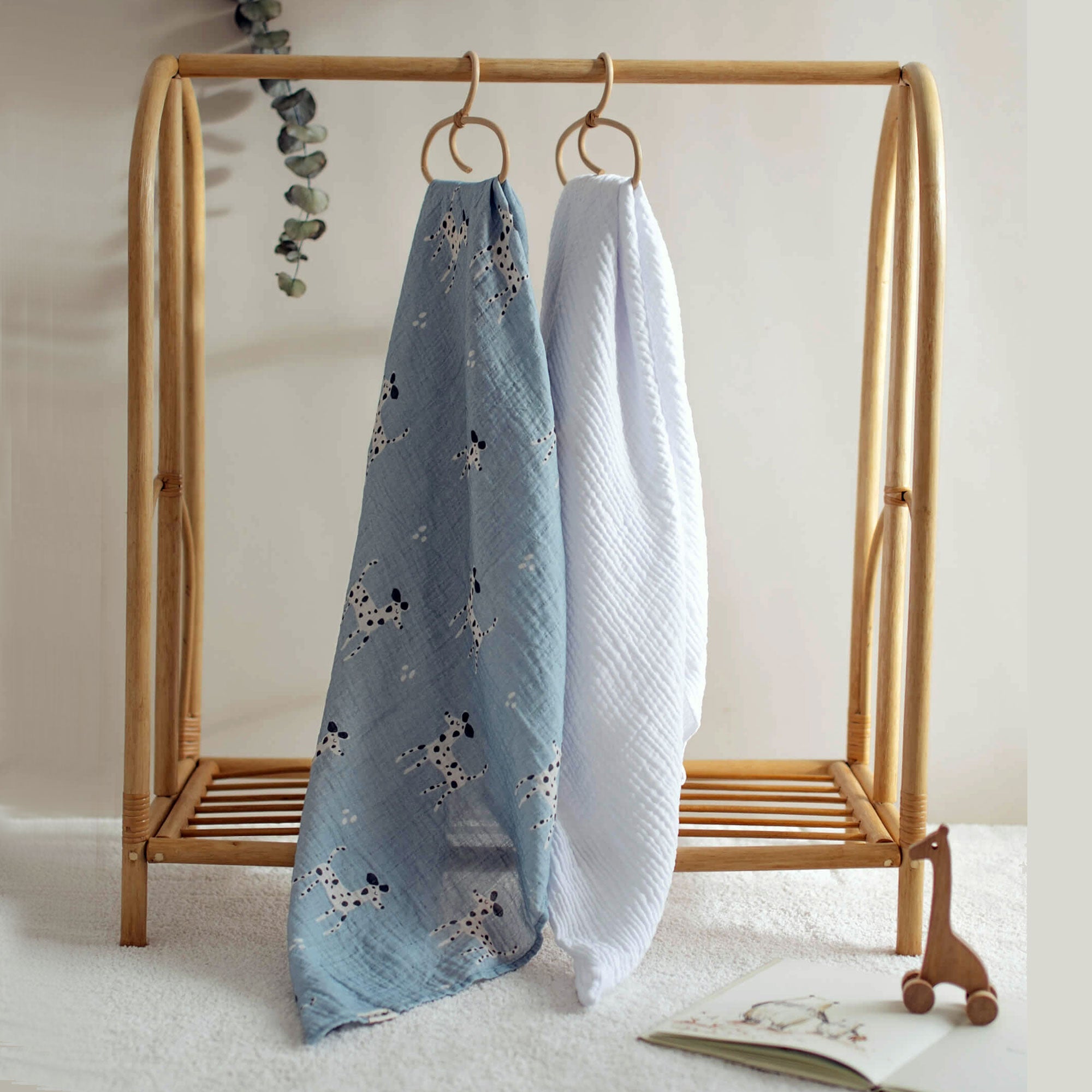 Dalmatian print swaddle and white blanket hanging side by side on rack