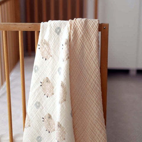 Fluffy Sheep baby swaddle draped over a wicker nursery chair