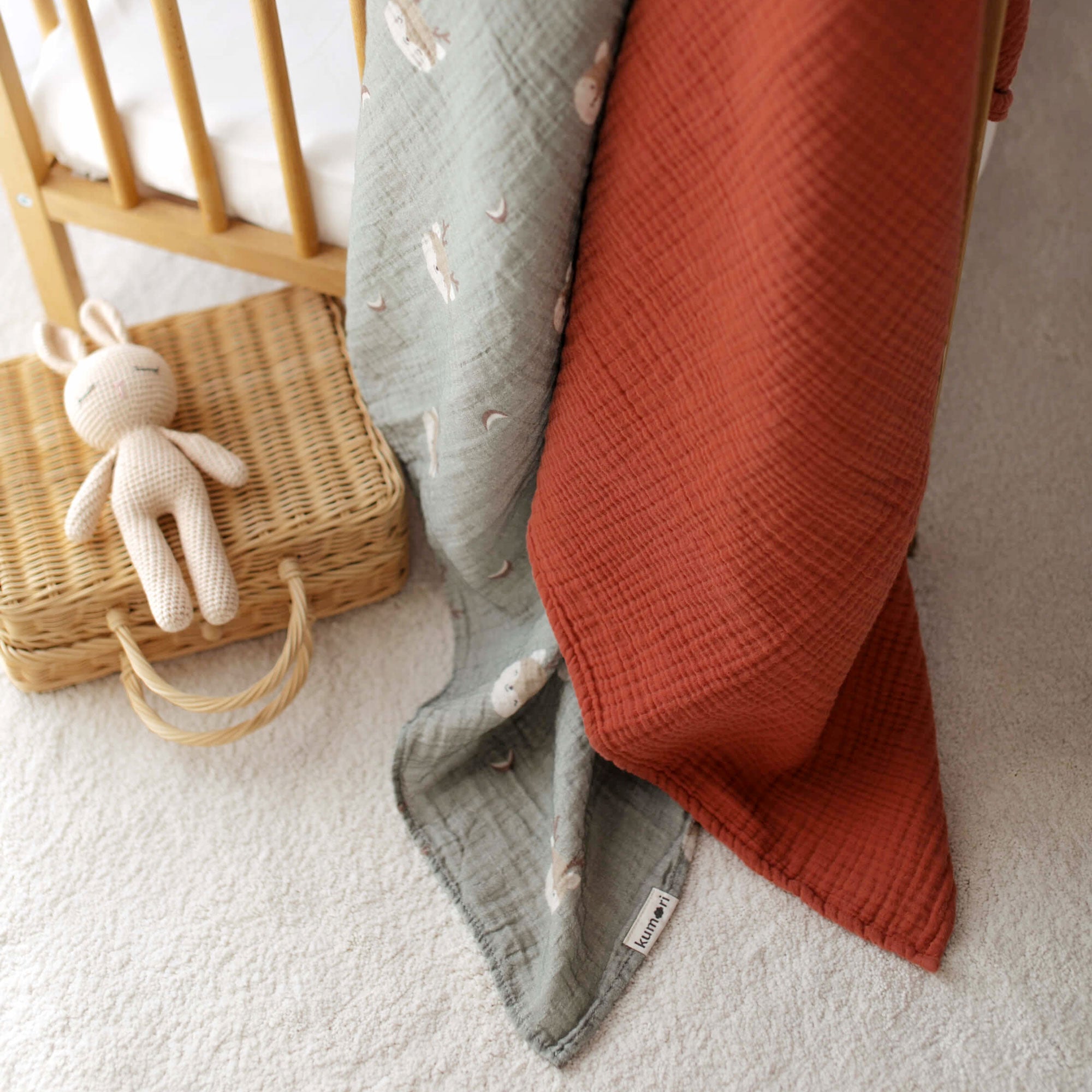 Close-up of Forest Deer swaddle and terra cotta blanket styled in nursery
