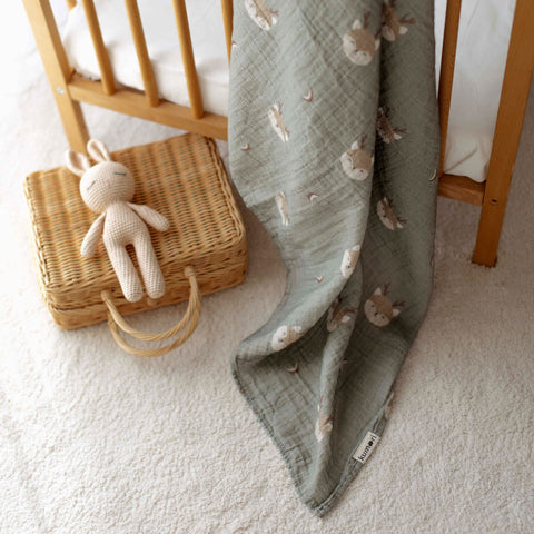 Close-up of Forest Deer muslin baby swaddle in soft green tones