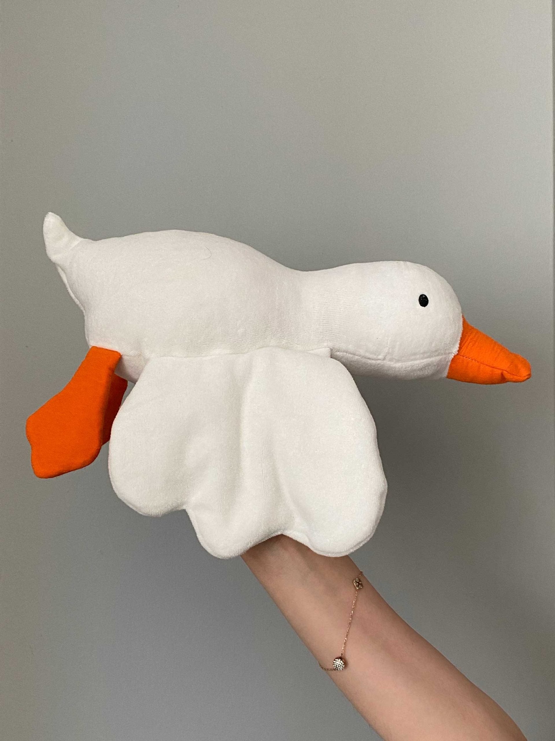 Gus the Goose plush toy held in hand, side view of head and wings