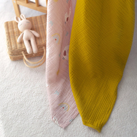 Lady Goose muslin swaddle layered over mustard muslin blanket in nursery
