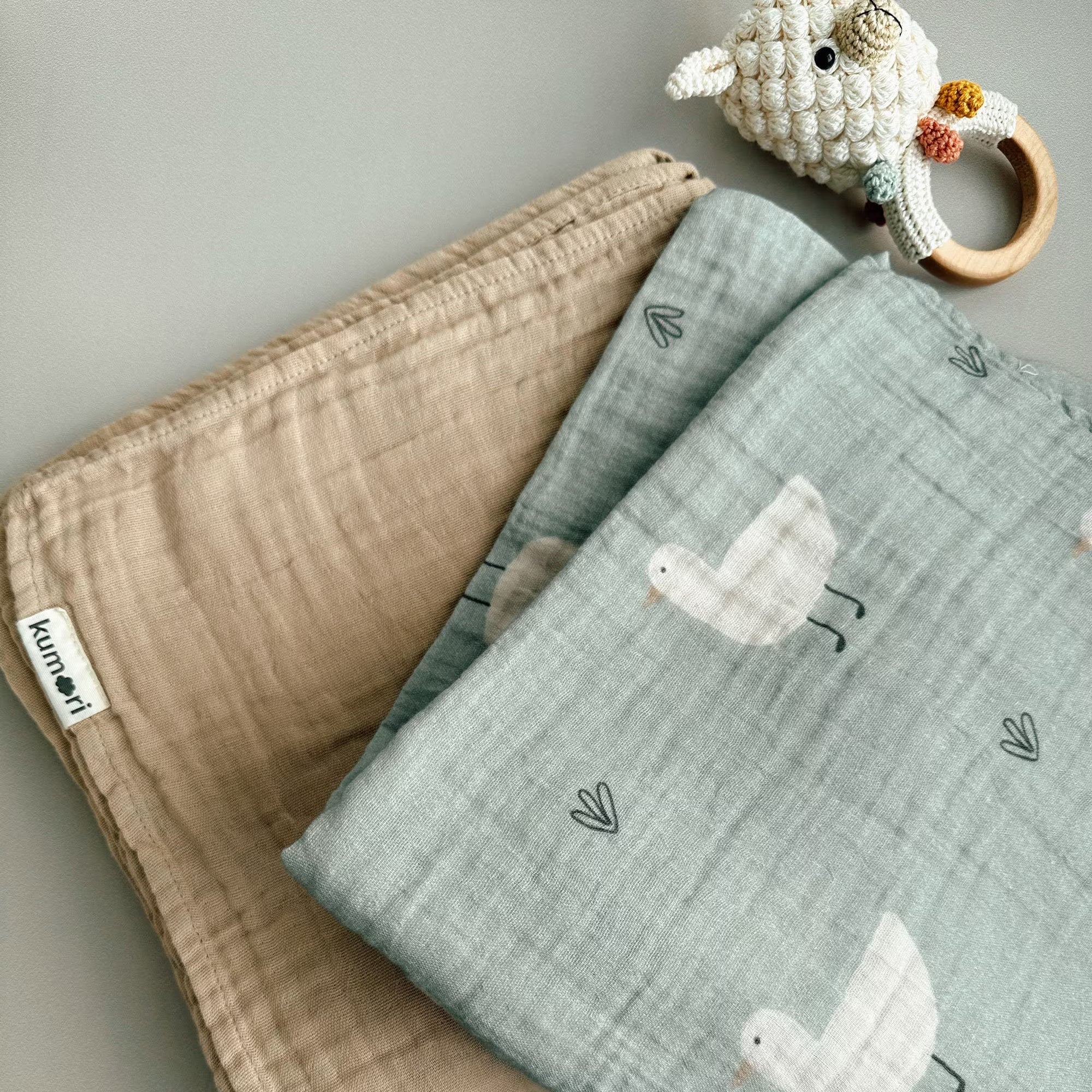 Close-up of Minty Duck swaddle folded with latte muslin blanket