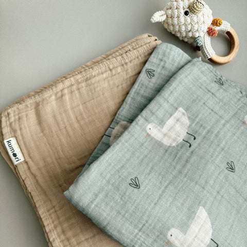 Close-up of Minty Duck swaddle folded with latte muslin blanket
